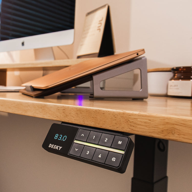 Black Desky bluetooth controller on wood standing desk