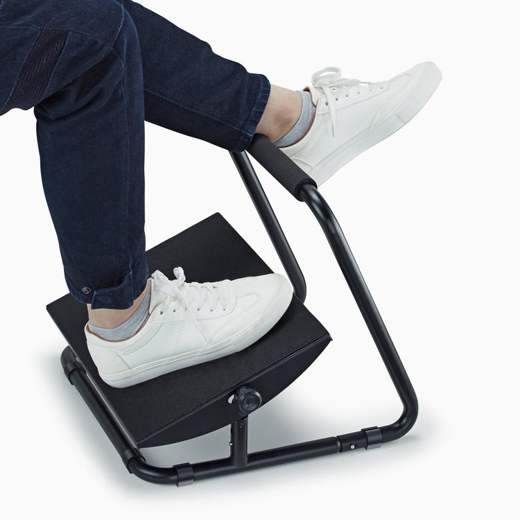 Person wearing white shoes using elevated footrest